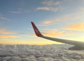 airplane wing over puffy clouds at sunset