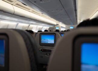 interior of a passenger plane with screens on the backs of the seats
